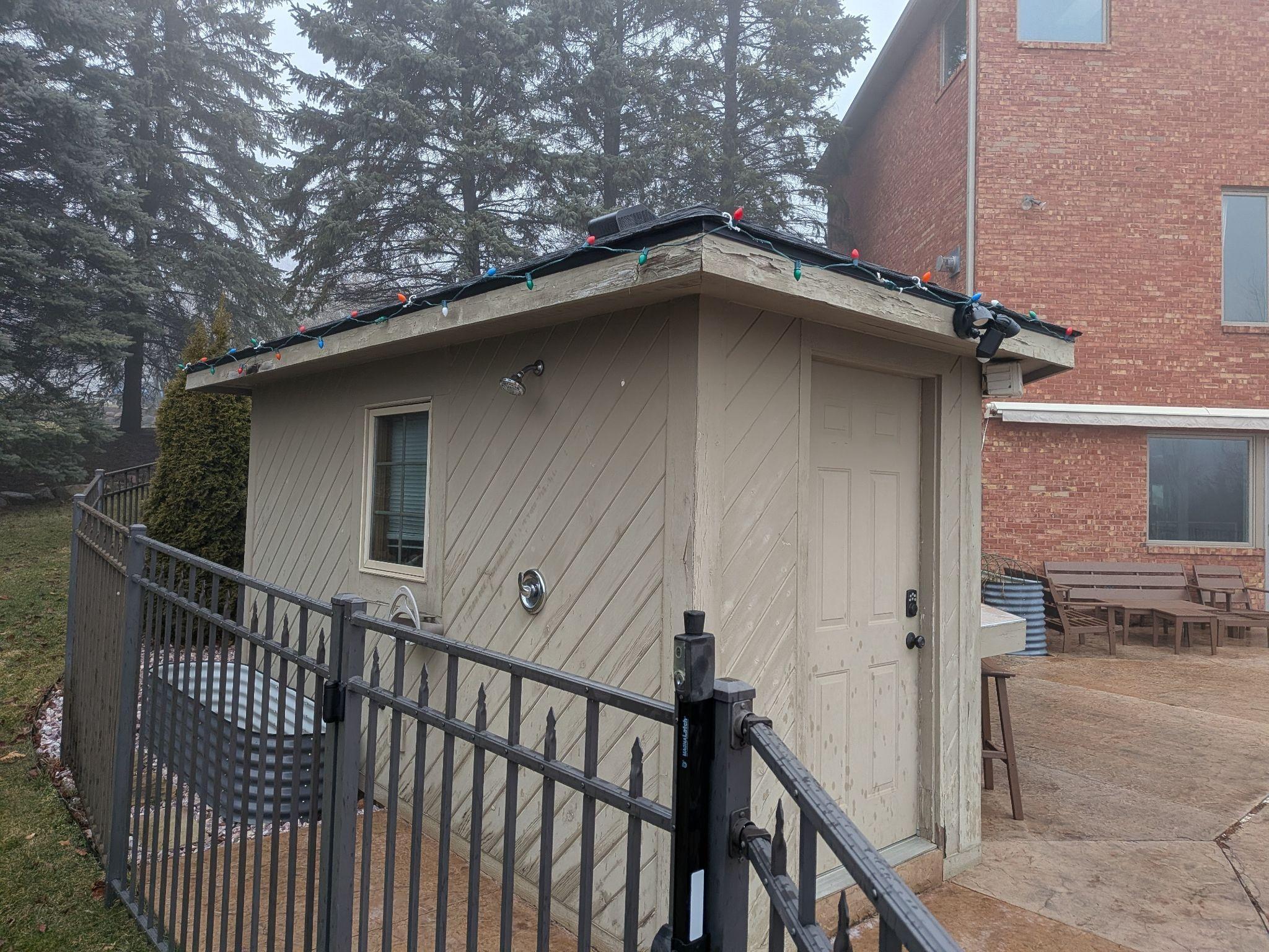Front of a pool house with worn diagonal siding and an old door
