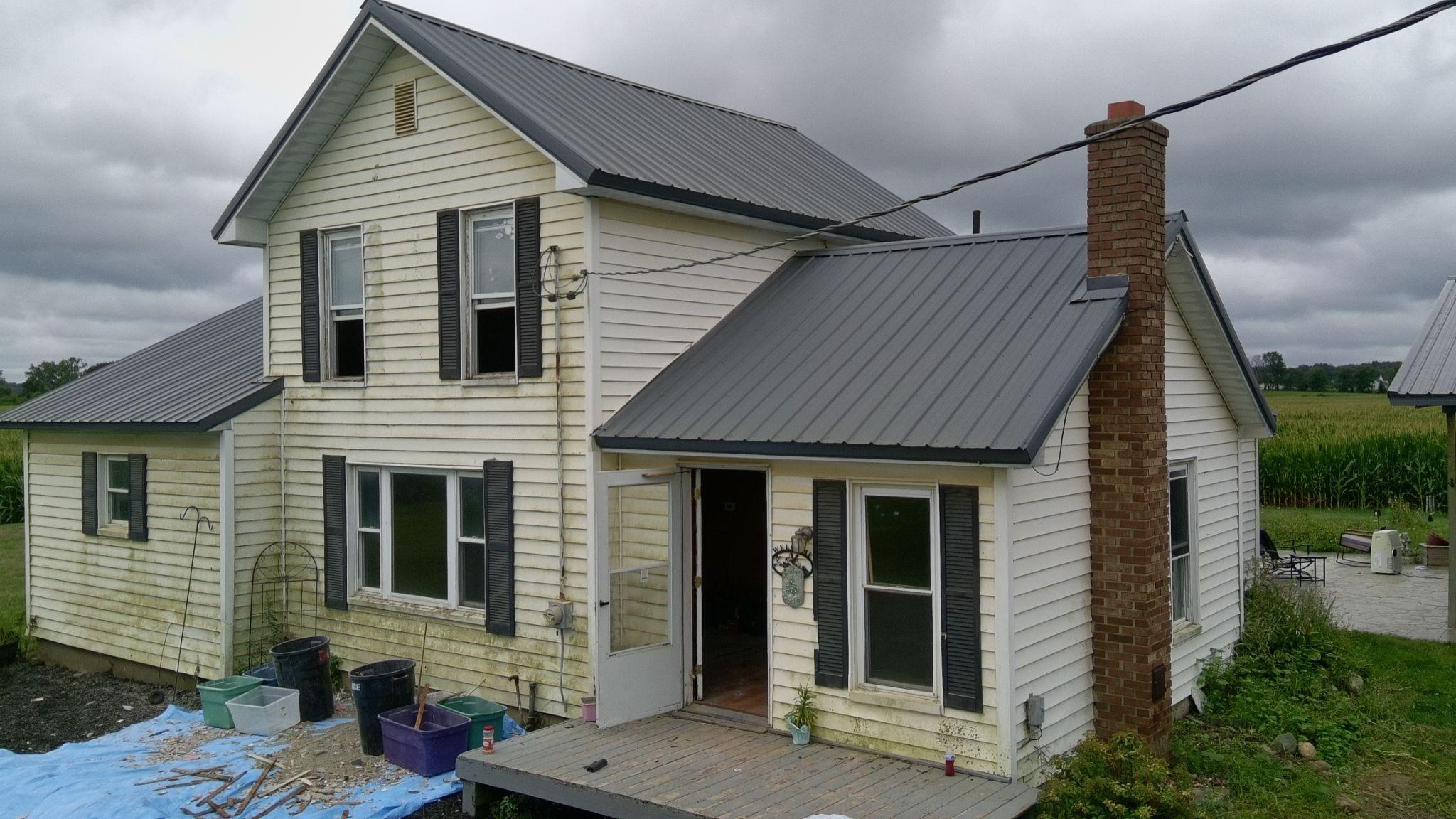Front of a two-story white farmhouse with a gray standing-seam metal roof