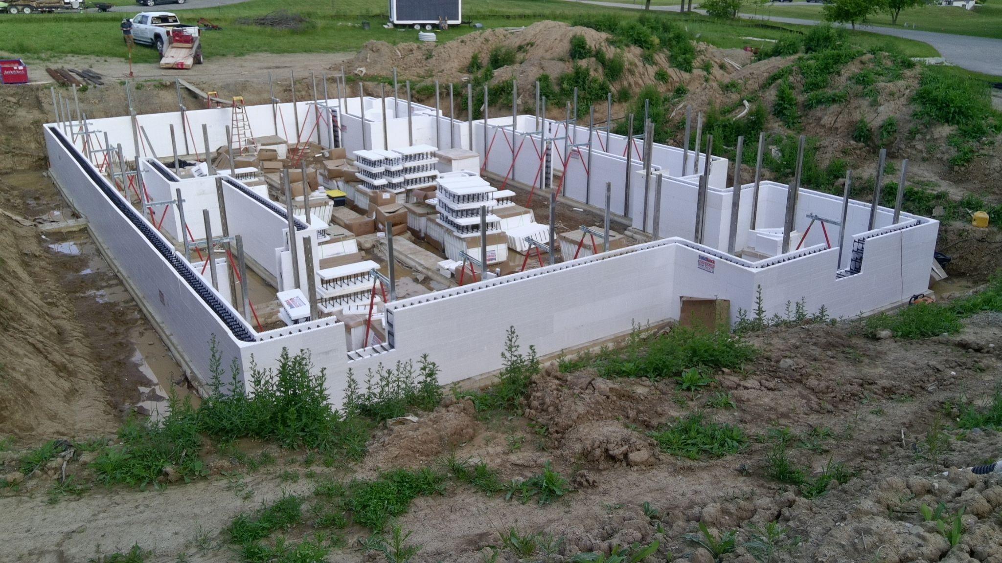 Aerial view of white ICF foundation walls with red bracing and vertical rebar inside an excavation