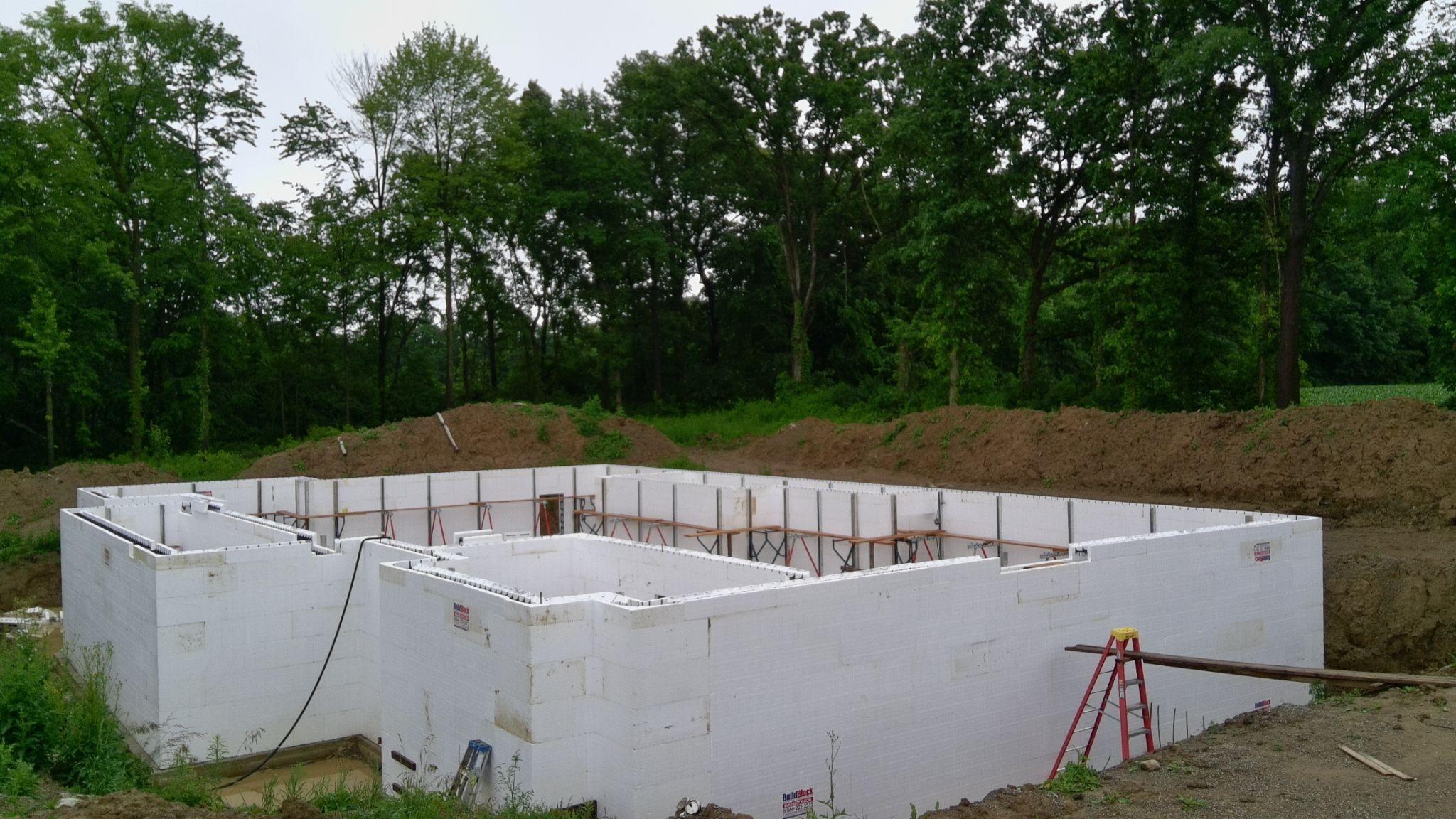 A completed white ICF foundation seen from above, with openings for windows and a door