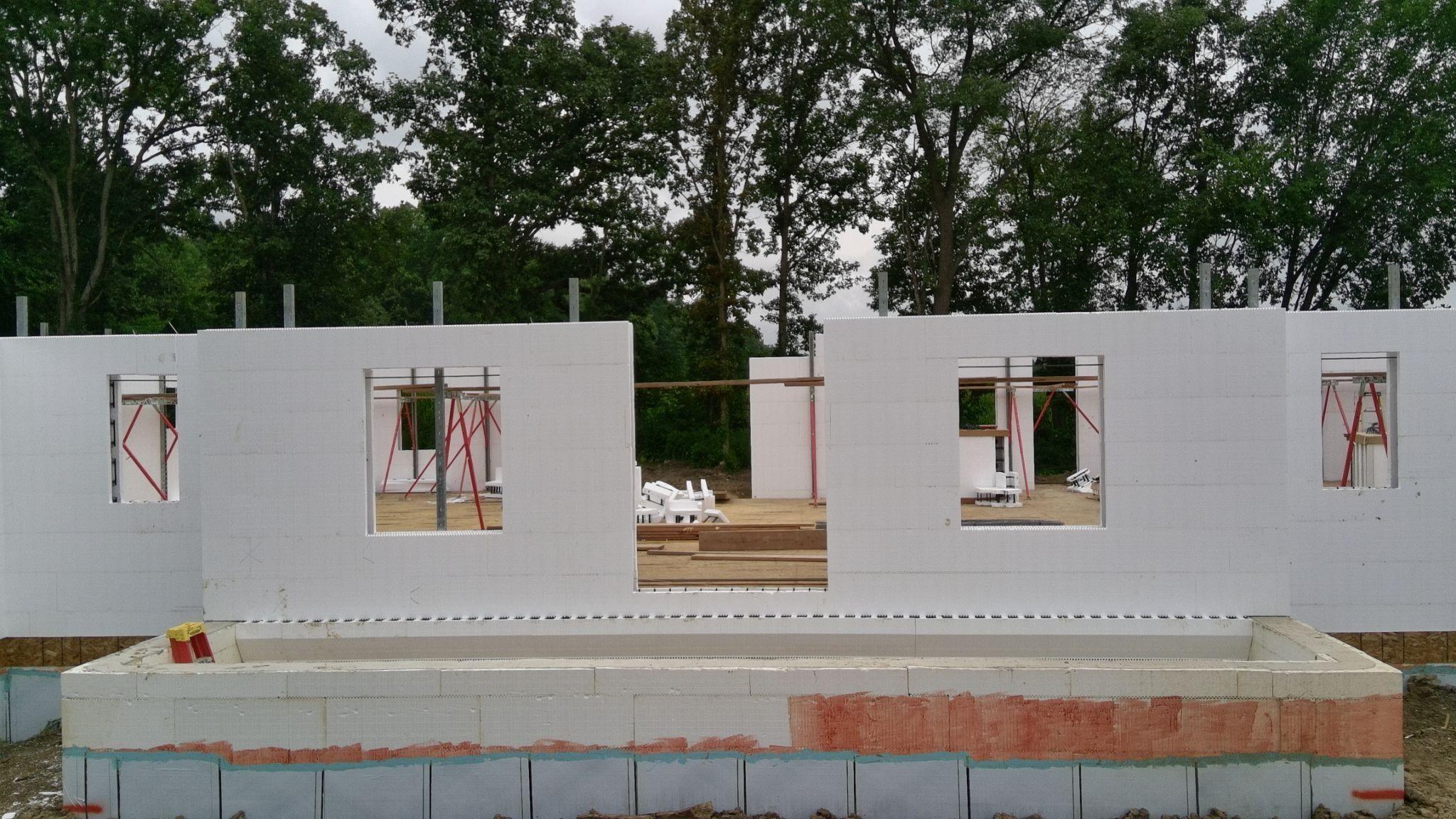 White ICF main-floor walls with wood window bucks standing on a concrete foundation
