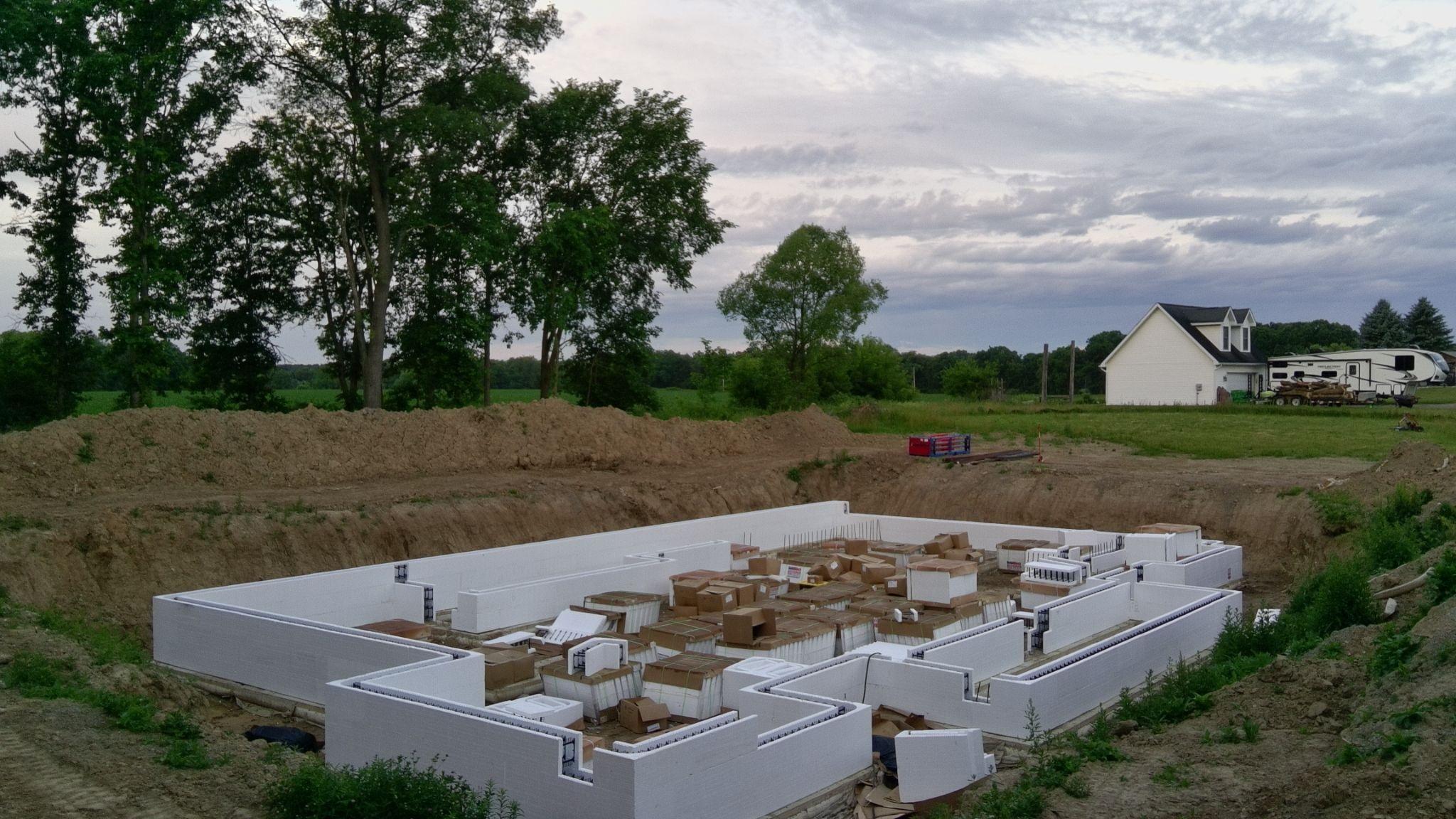 Partially stacked white ICF foundation walls inside an excavation, viewed from above
