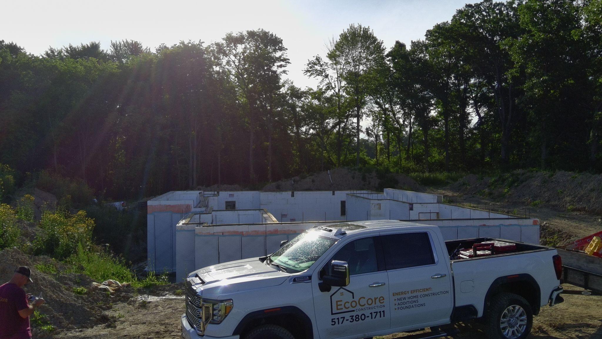 An EcoCore Construction pickup truck parked beside a poured ICF foundation in the evening sun