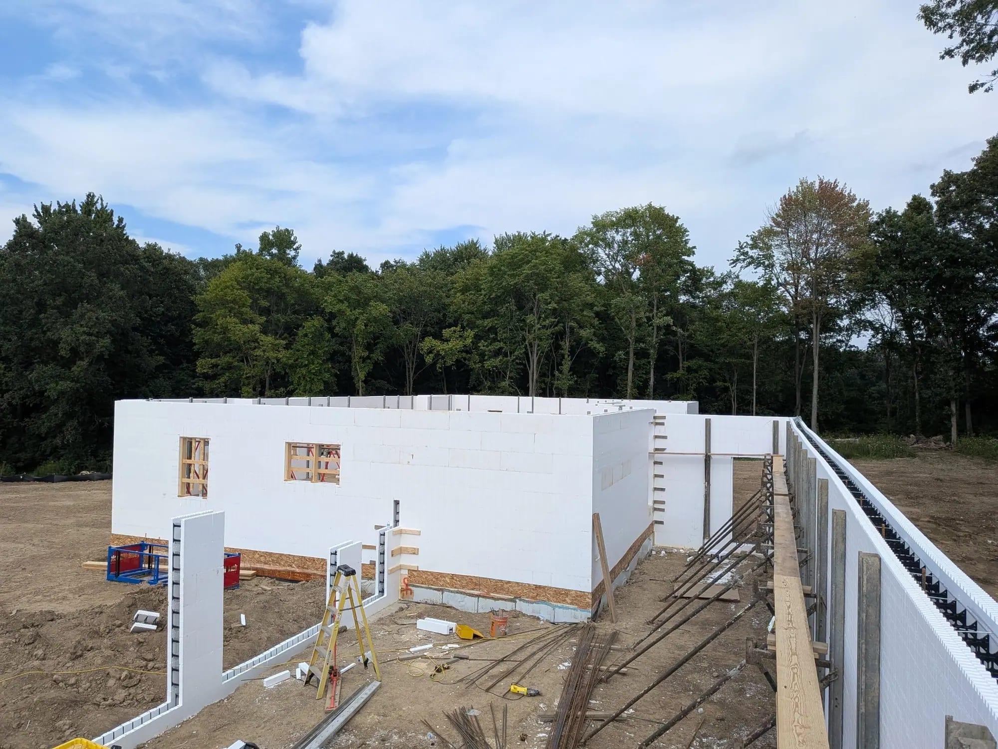 ICF walls with window bucks and bracing on a dirt site with trees behind