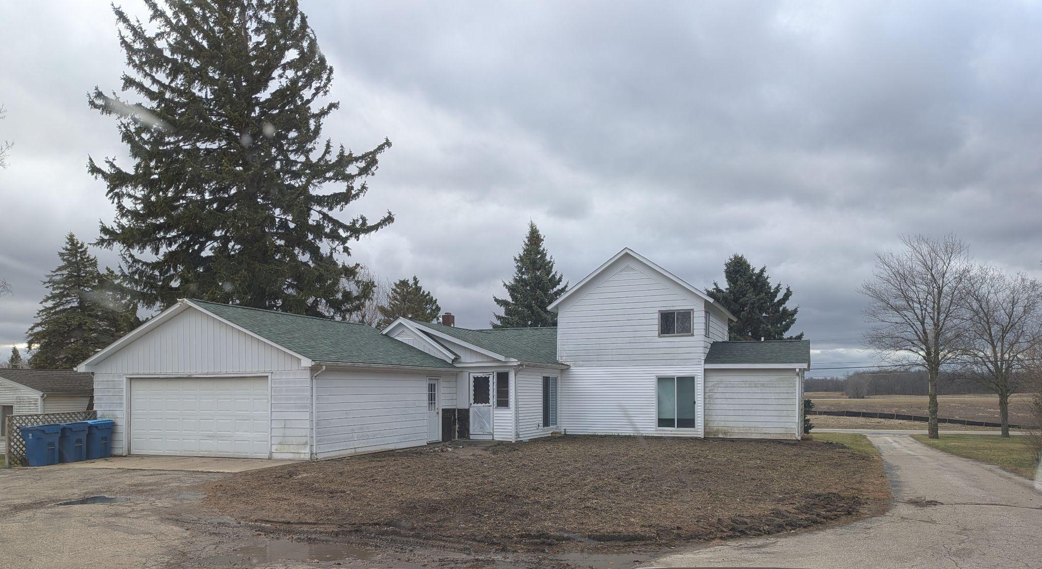 An older white two-story house with an attached garage, photographed before work began