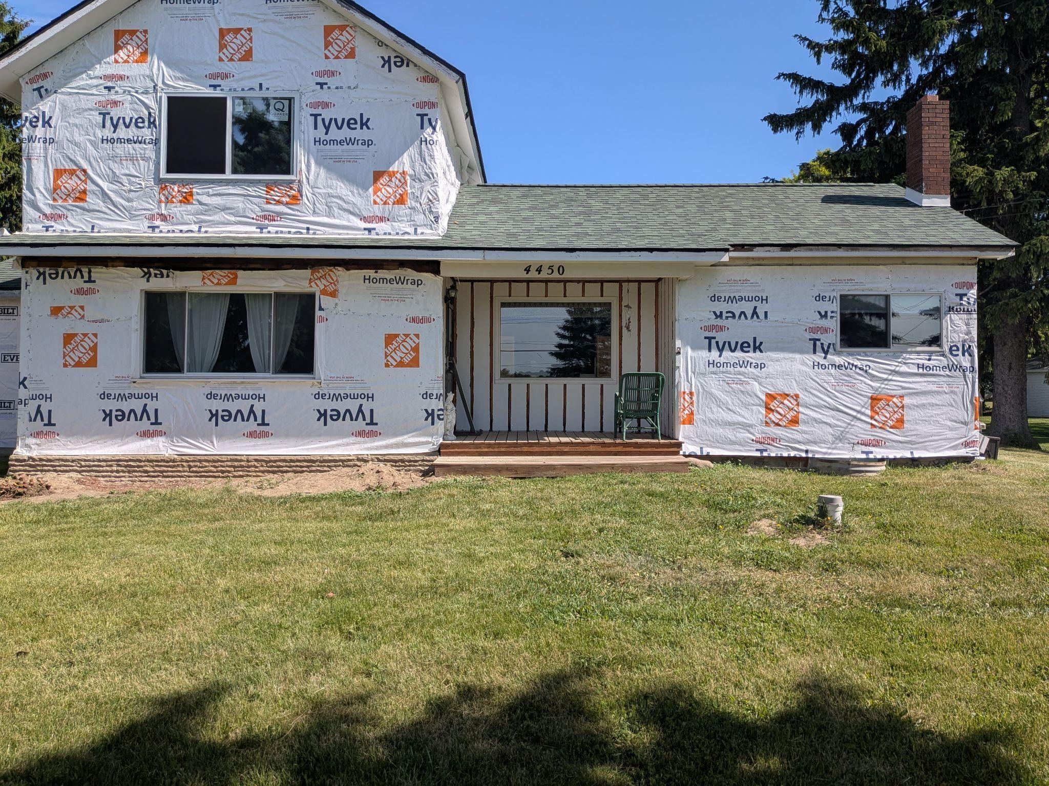 A house wrapped in house-wrap with old siding removed, ready for new siding